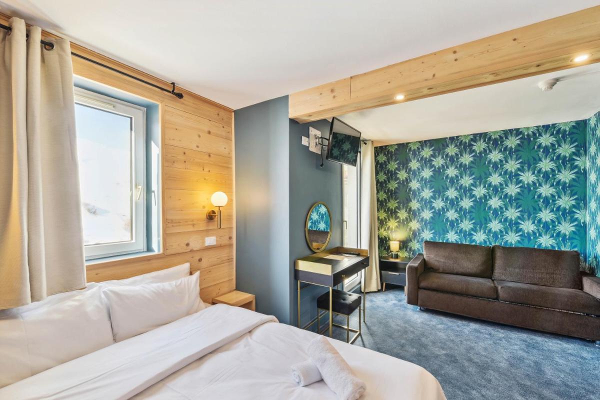 une chambre avec un lit et un canapé dans l'établissement Hotel Turan & Spa, à Les Deux Alpes