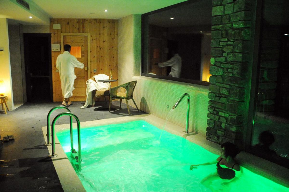 un hombre de pie junto a una bañera en una habitación de hotel en Bonansa Country Hotel, en Bonansa