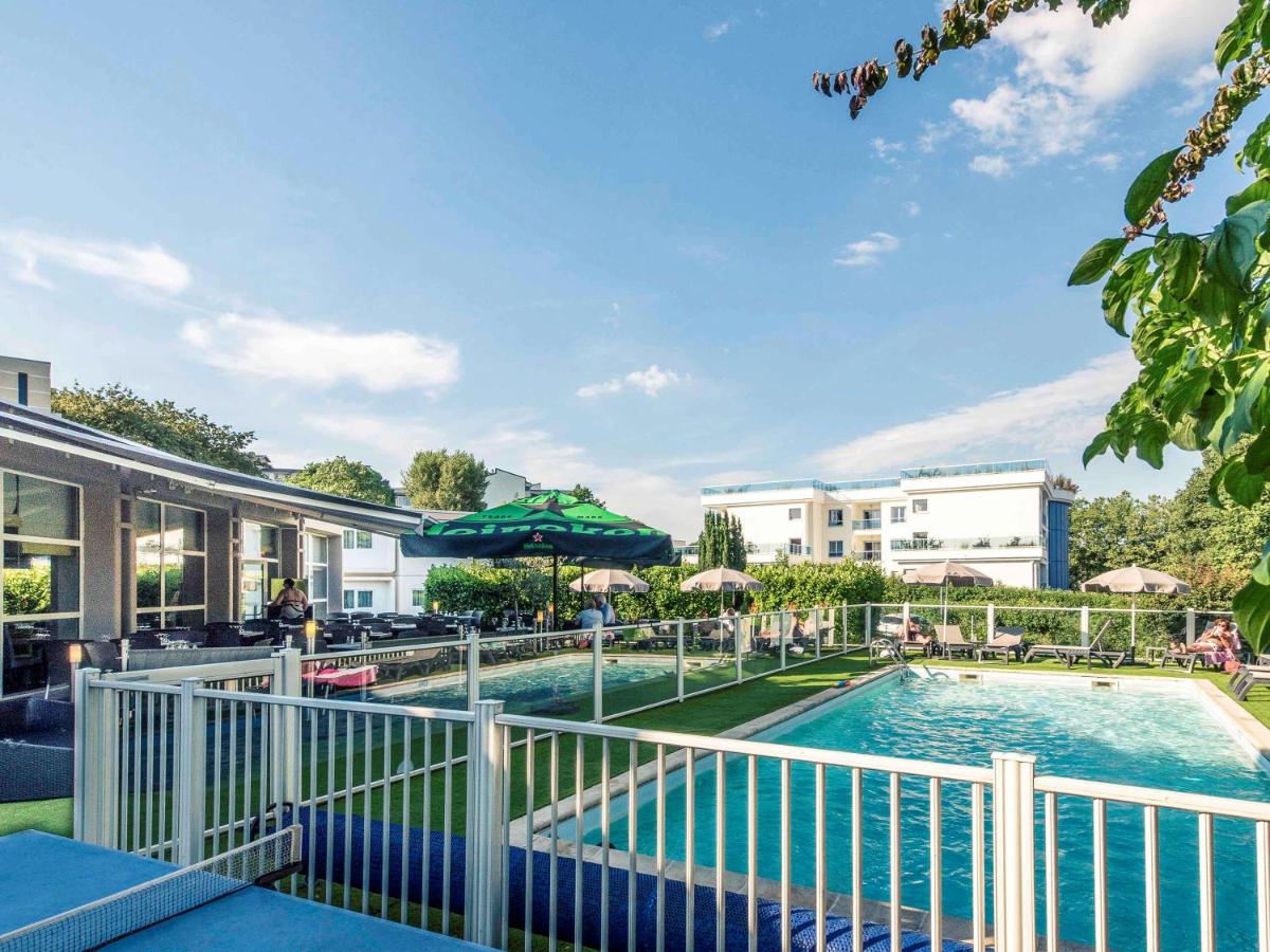 une piscine dans un complexe hôtelier avec des chaises longues et des parasols dans l'établissement Mercure Annecy Sud, à Annecy