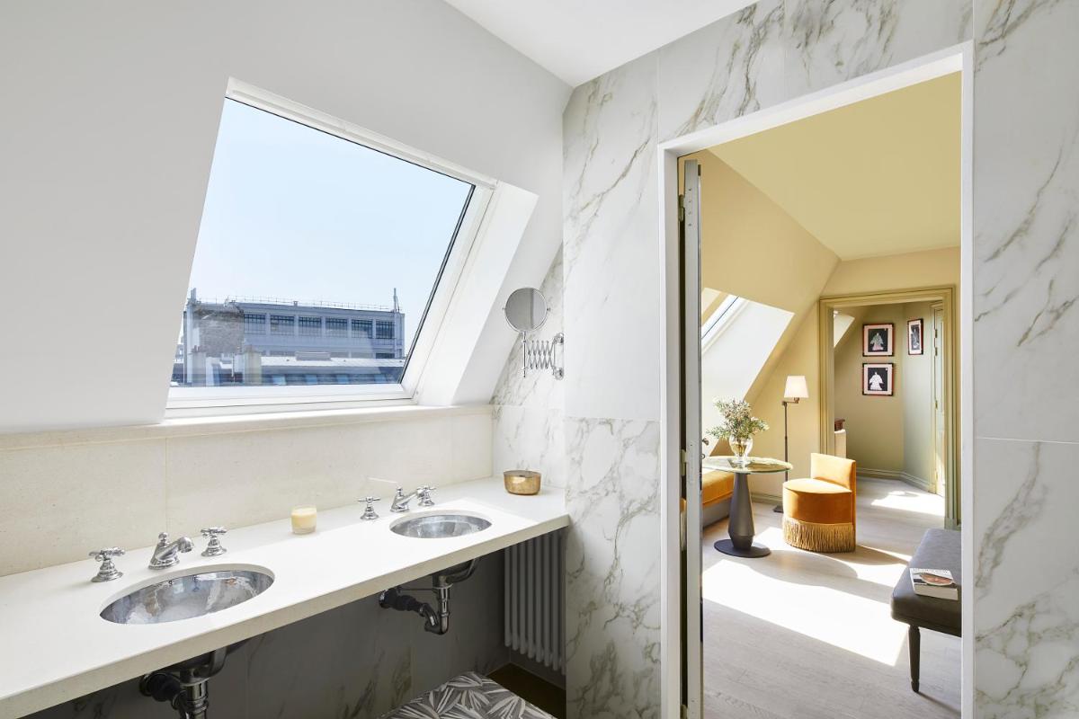 une salle de bain avec deux lavabos et une fenêtre dans l'établissement Hotel de Montesquieu, à Paris