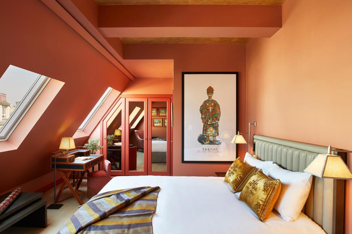 une chambre avec des murs orange et un lit dans une pièce dans l'établissement Hotel de Montesquieu, à Paris