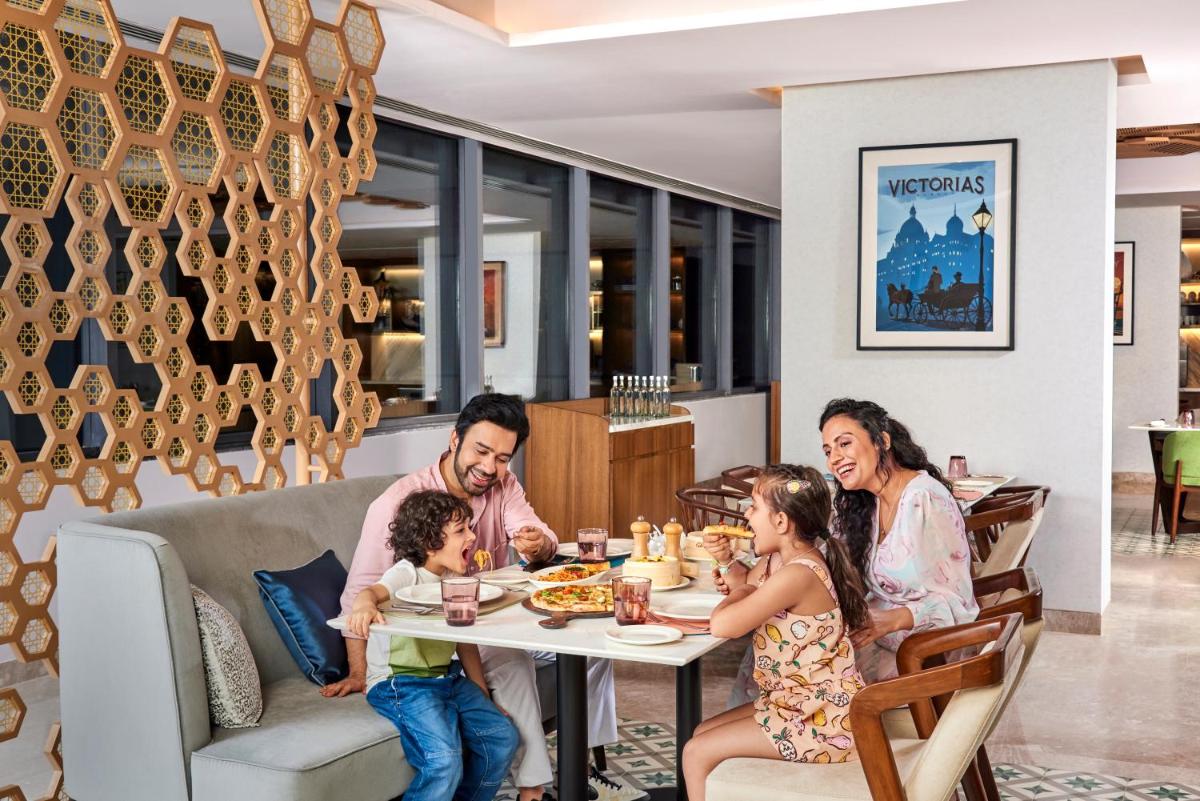 a family sitting at a table in a restaurant at Novotel Mumbai International Airport in Mumbai