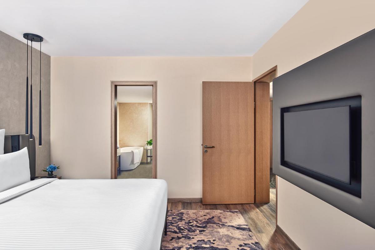 a bedroom with a bed and a flat screen tv at Novotel Mumbai International Airport in Mumbai