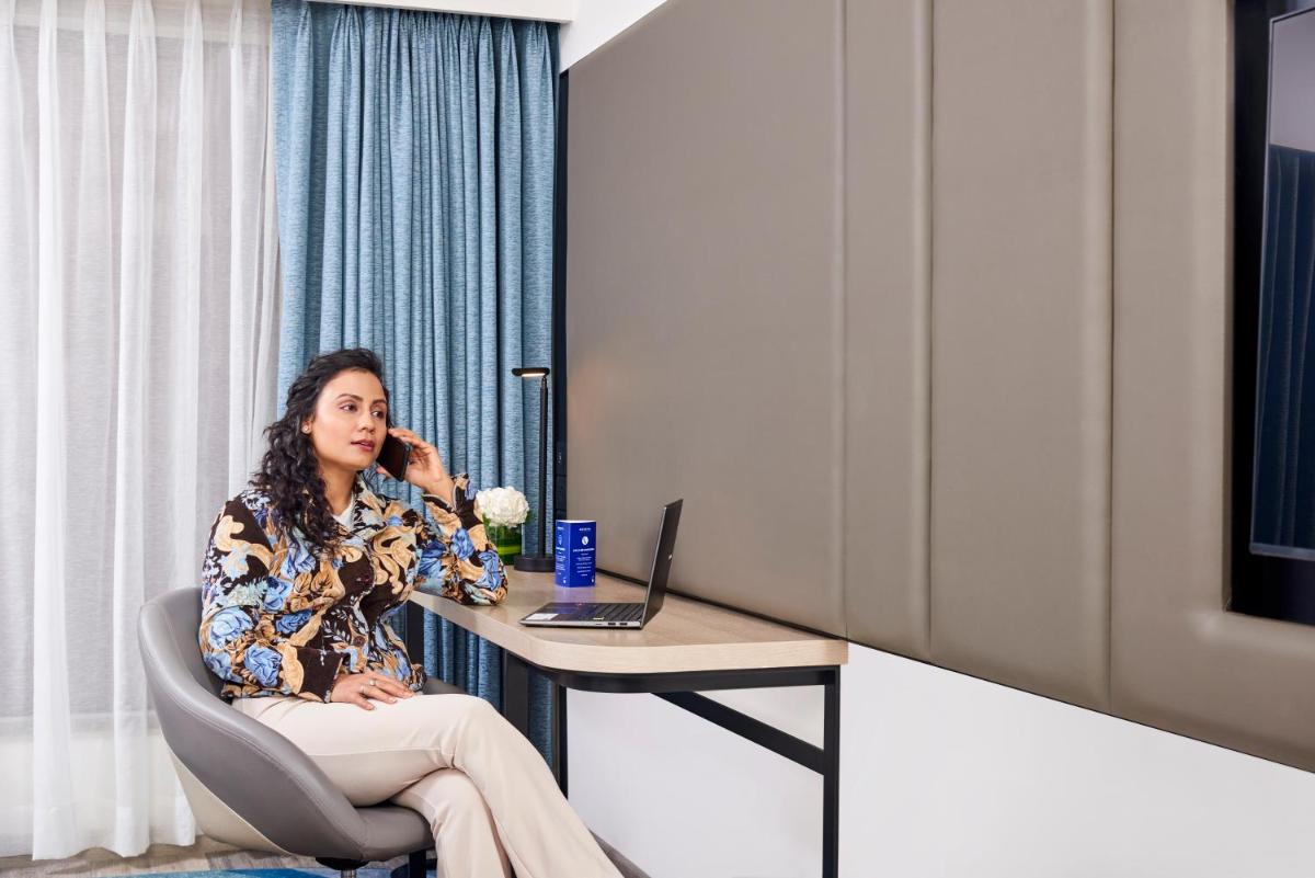 a woman sitting at a table talking on a cell phone at Novotel Mumbai International Airport in Mumbai