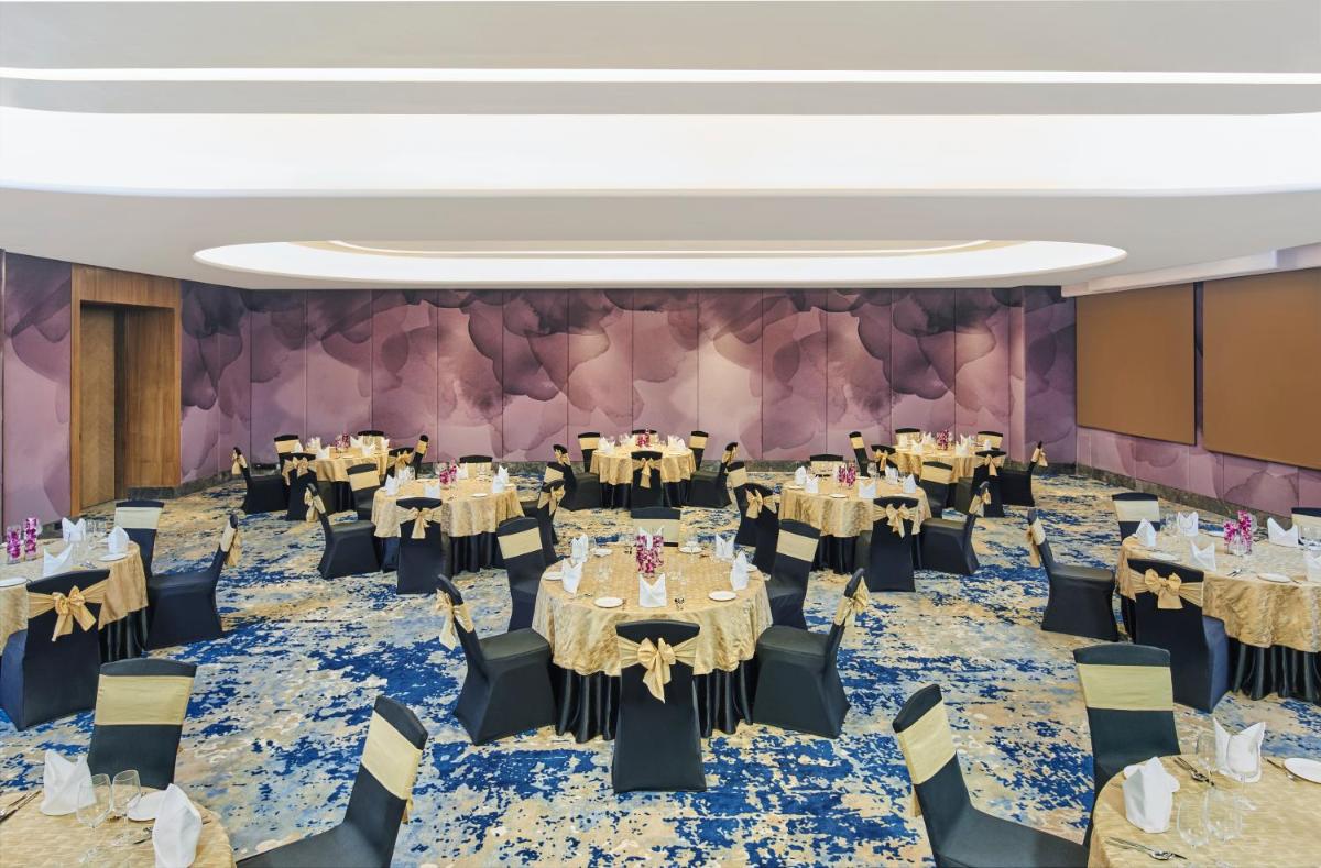 a banquet hall with tables and chairs and a wall at Novotel Mumbai International Airport in Mumbai