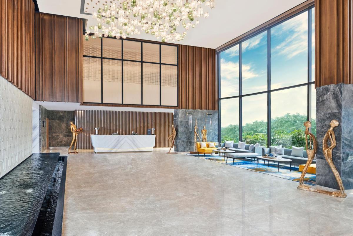 a lobby with a table and chairs and large windows at Novotel Mumbai International Airport in Mumbai