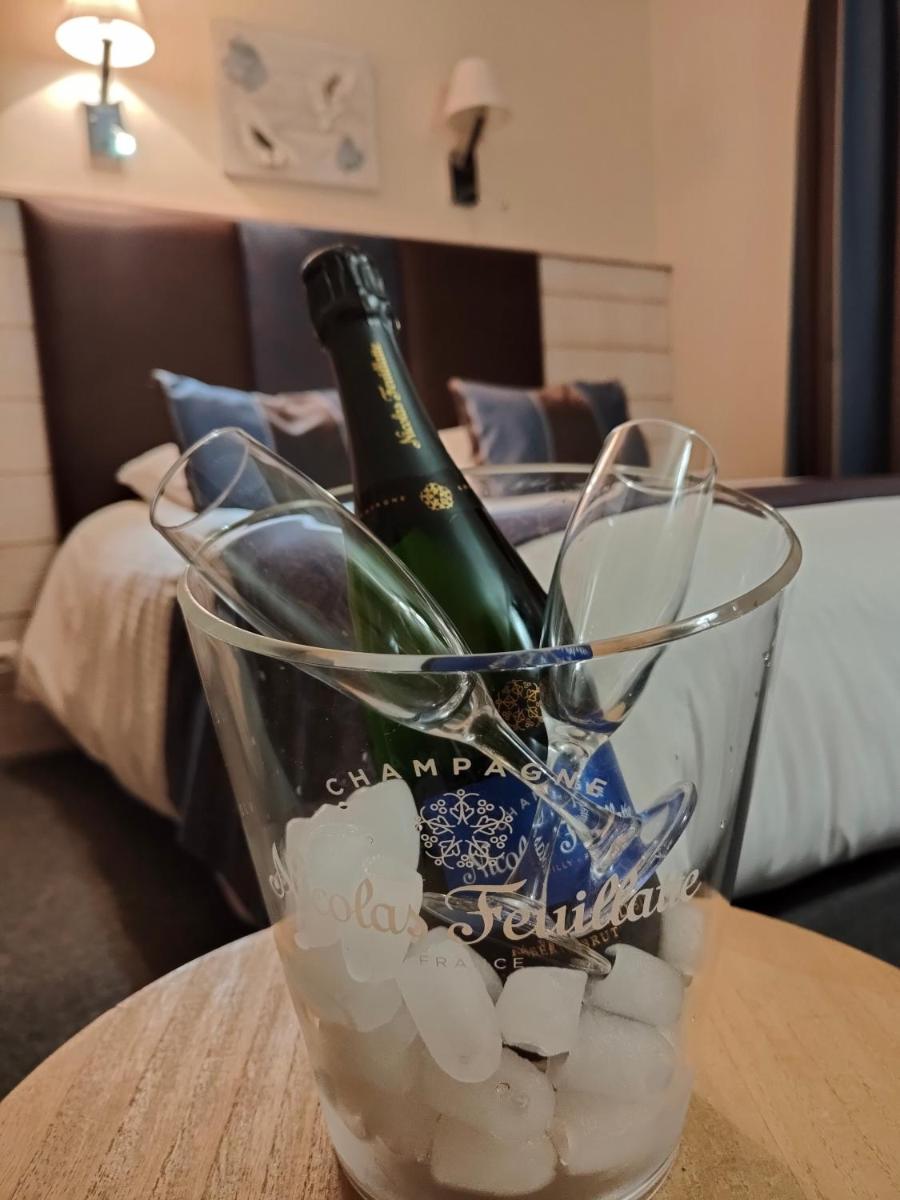 - une bouteille de champagne dans un bol en verre sur une table dans l'établissement Hôtel Spa & Restaurant Ô Pervenches, à Chambéry