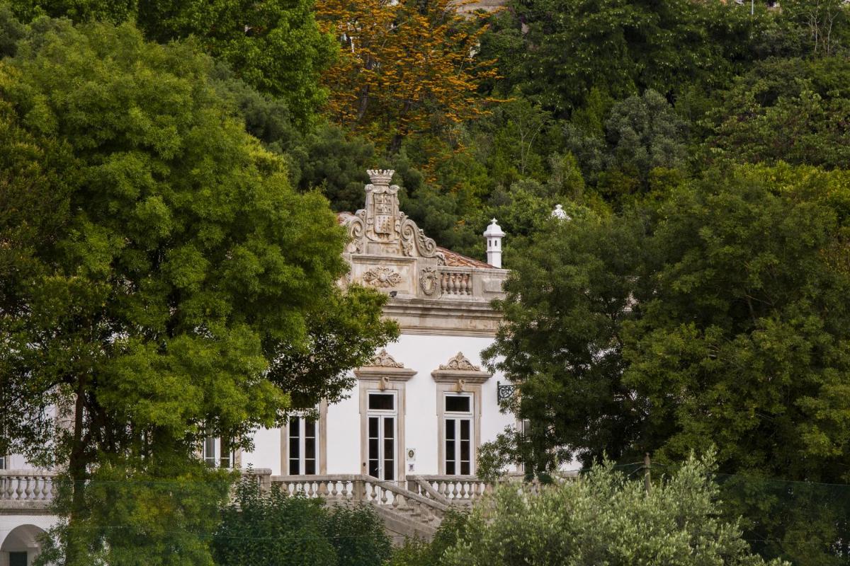uma casa branca com árvores em frente a ela em Hotel Quinta das Lagrimas - Small Luxury Hotels em Coimbra