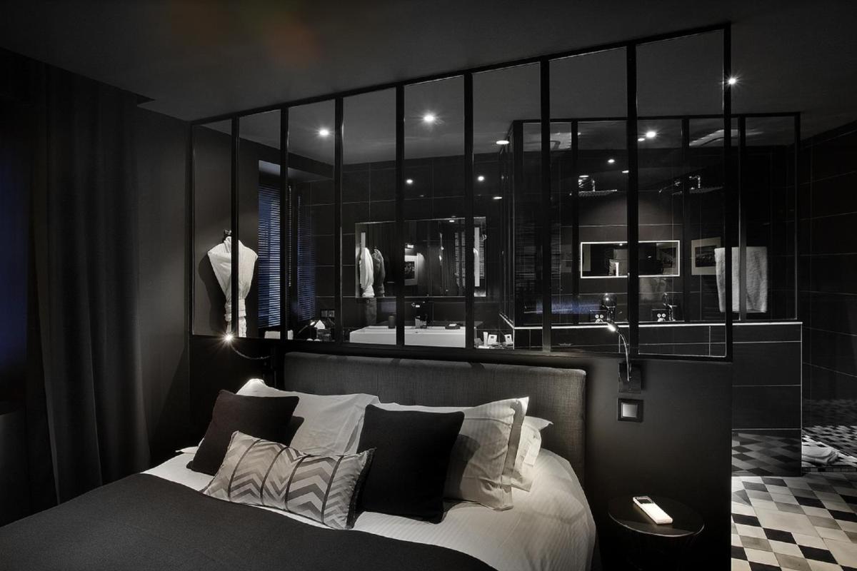 une chambre avec un lit avec des oreillers noirs et blancs dans l'établissement Petit Hôtel Confidentiel, à Chambéry