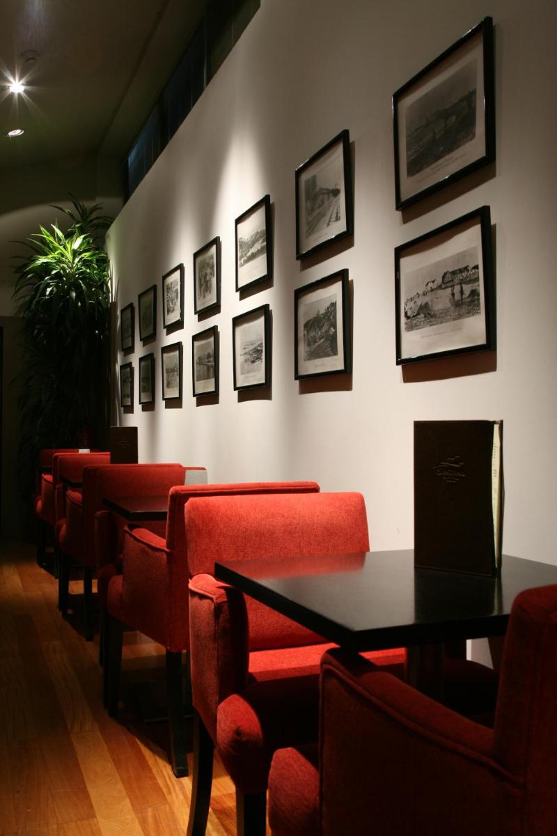 uma sala de jantar com cadeiras vermelhas e quadros na parede em Santana Hotel & SPA em Vila do Conde