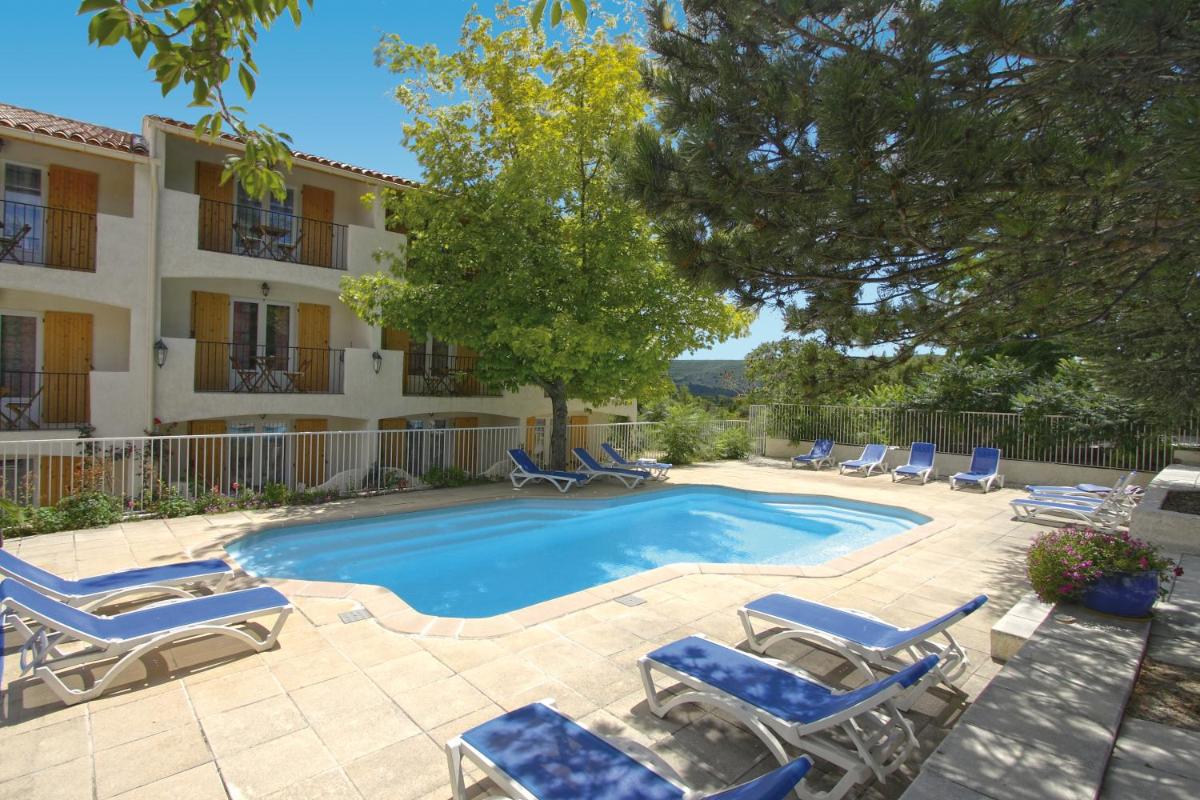 une piscine avec des chaises longues et un bâtiment dans l'établissement Hôtel Spa L'Ermitage, aux Salles-sur-Verdon