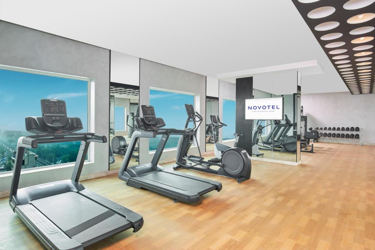 a gym with several tread machines in a room at Novotel Mumbai International Airport in Mumbai