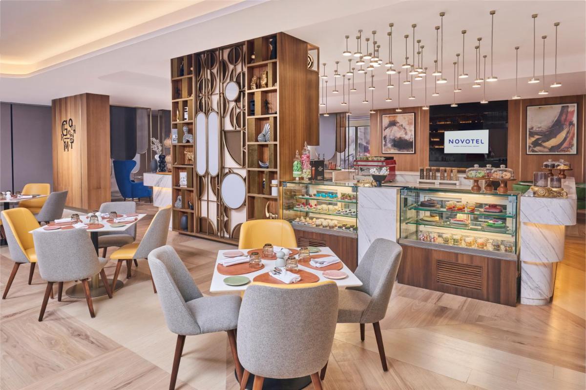 a restaurant with tables and chairs and a counter at Novotel Mumbai International Airport in Mumbai