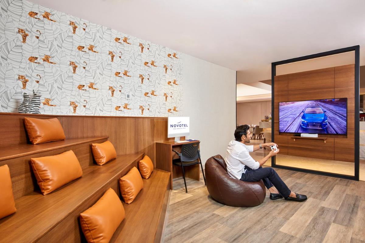 a woman sitting in a chair watching a tv at Novotel Mumbai International Airport in Mumbai