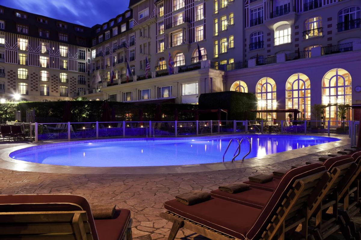une grande piscine devant un immeuble la nuit dans l'établissement Hôtel Barrière Le Royal Deauville, à Deauville une grande piscine devant un immeuble la nuit dans l'établissement Hôtel Barrière Le Royal Deauville, à Deauville