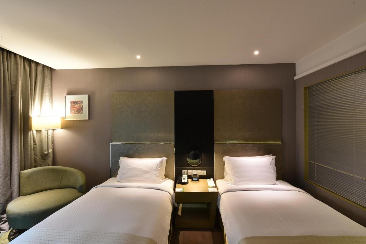 a hotel room with two beds and a chair at Holiday Inn New Delhi Aerocity by IHG in New Delhi