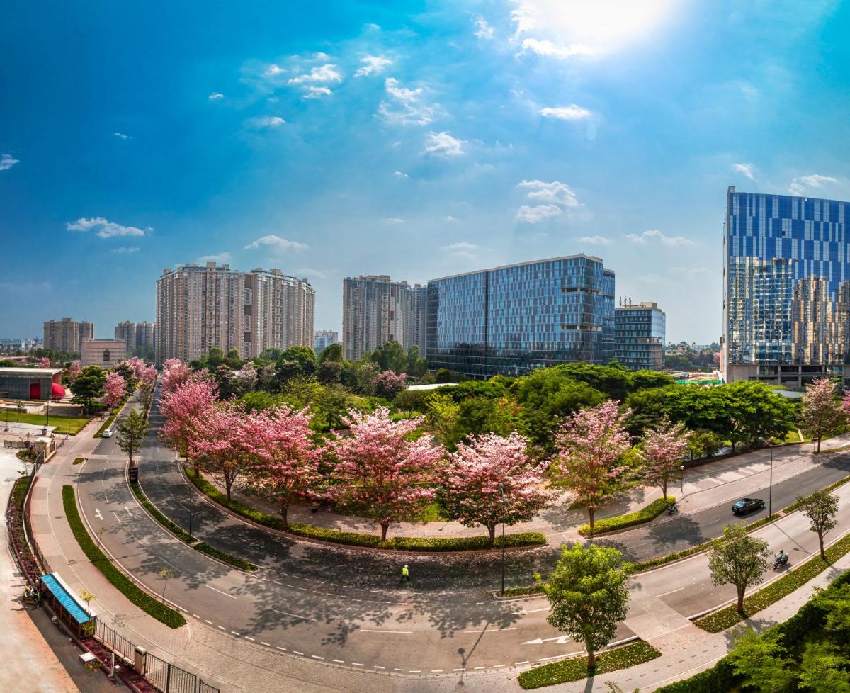 a city withakura trees in a park with tall buildings at The Leela Bhartiya City Bengaluru in Bengaluru a city withakura trees in a park with tall buildings at The Leela Bhartiya City Bengaluru in Bengaluru