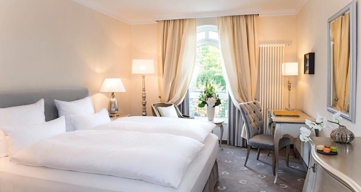 ein Hotelzimmer mit zwei Betten, einem Schreibtisch und einem Fenster in der Unterkunft Victor's Residenz-Hotel Schloss Berg in Nennig