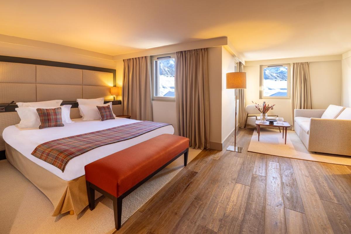 une chambre d'hôtel avec un grand lit et un canapé dans l'établissement Les Suites de la Potinière, à Courchevel
