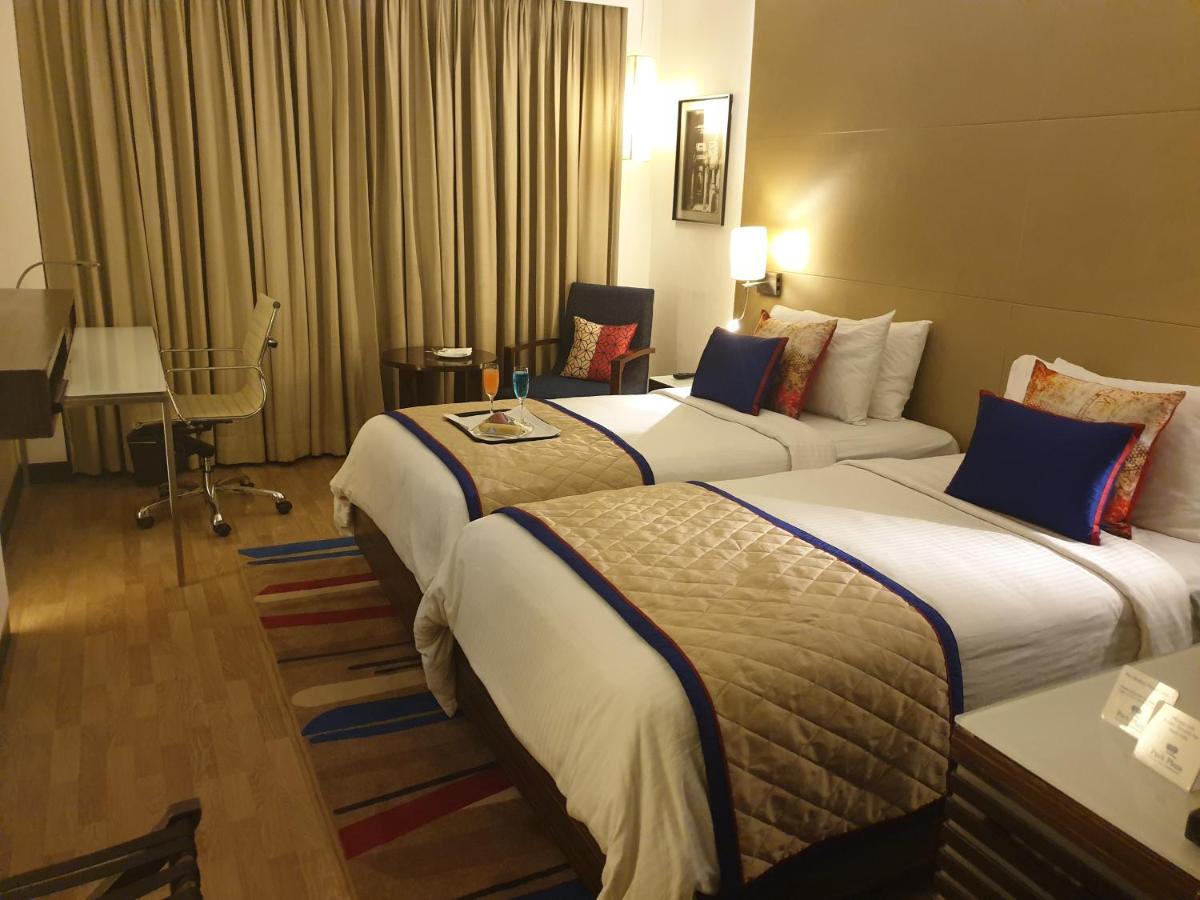 a hotel room with two beds and a table at Park Plaza Shahdara in New Delhi a hotel room with two beds and a table at Park Plaza Shahdara in New Delhi