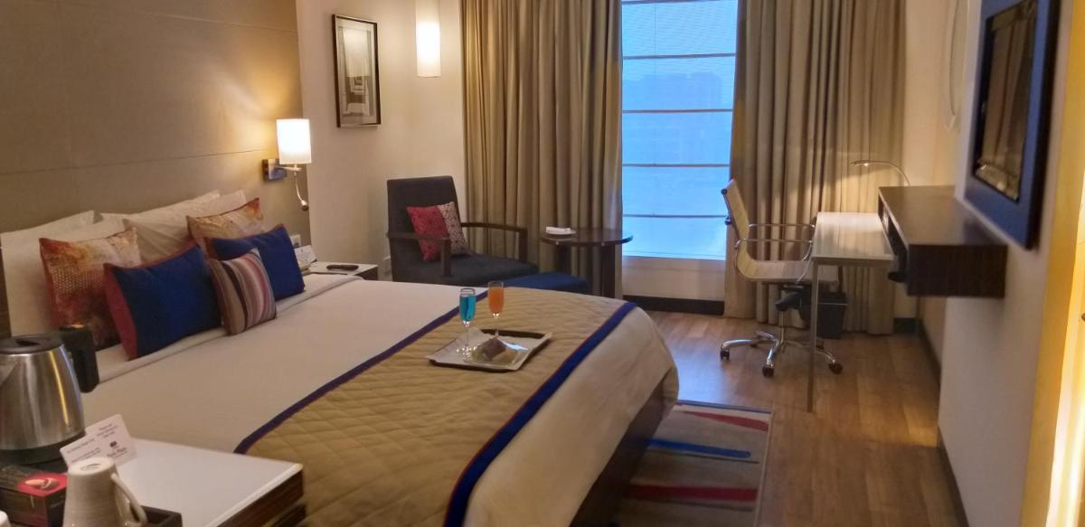 a hotel room with a large bed and a television at Park Plaza Shahdara in New Delhi a hotel room with a large bed and a television at Park Plaza Shahdara in New Delhi