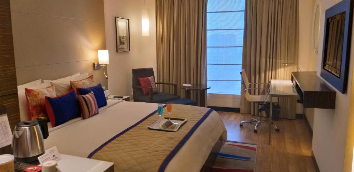 a hotel room with a large bed and a desk at Park Plaza Shahdara in New Delhi a hotel room with a large bed and a desk at Park Plaza Shahdara in New Delhi