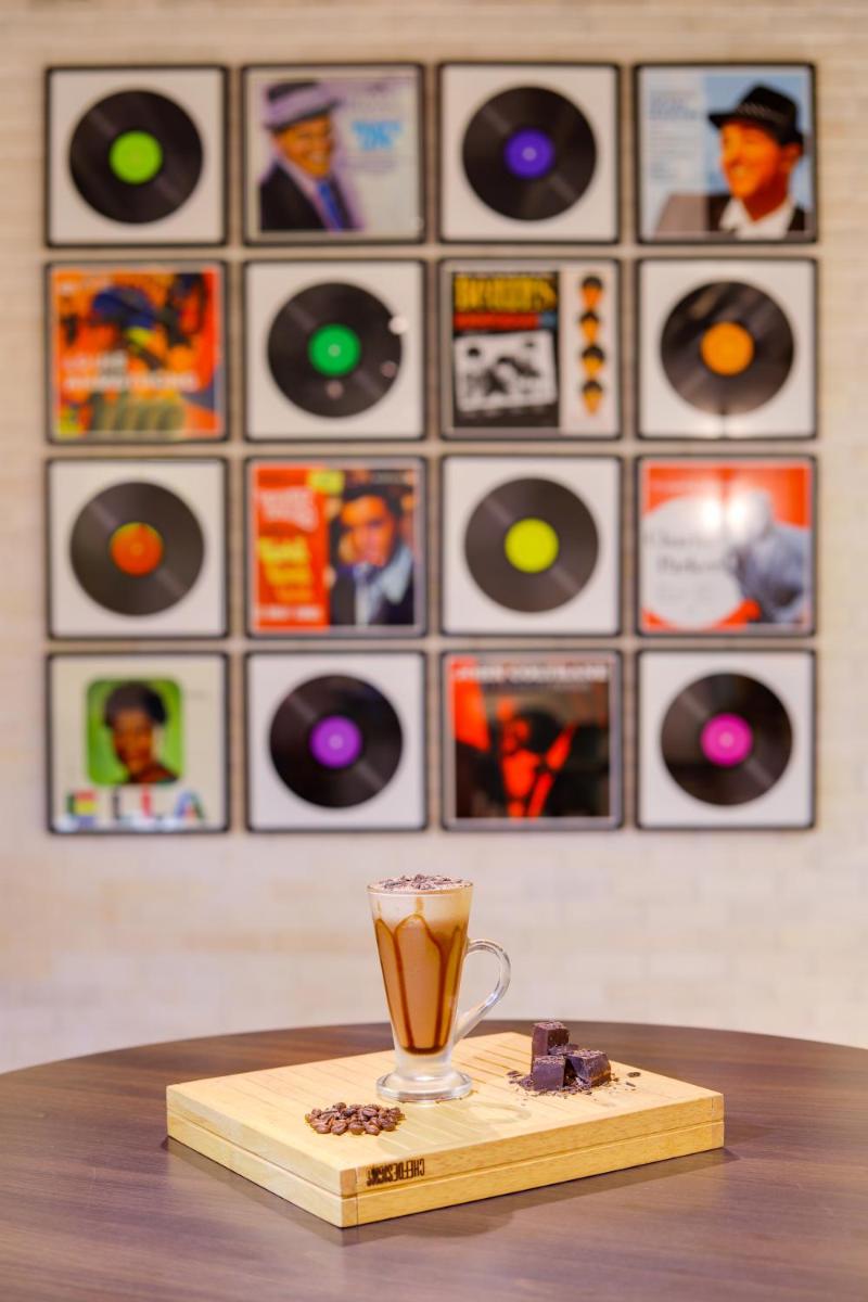 a cup of coffee sitting on a table with records at Lemon Tree Premier, Mumbai International Airport in Mumbai