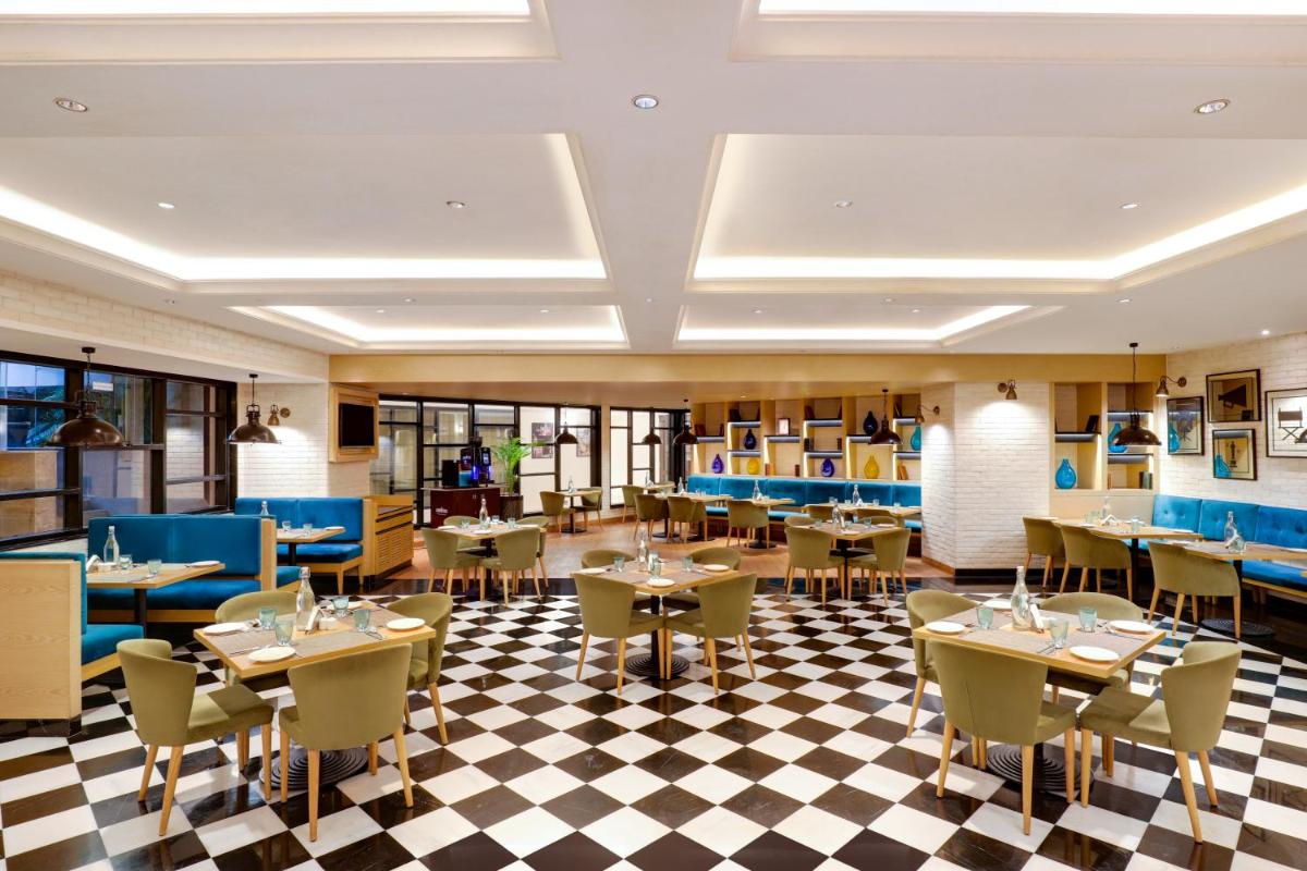 a restaurant with tables and chairs on a checkered floor at Lemon Tree Premier, Mumbai International Airport in Mumbai