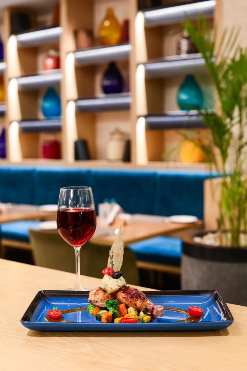 a plate of food and a glass of wine on a table at Lemon Tree Premier, Mumbai International Airport in Mumbai