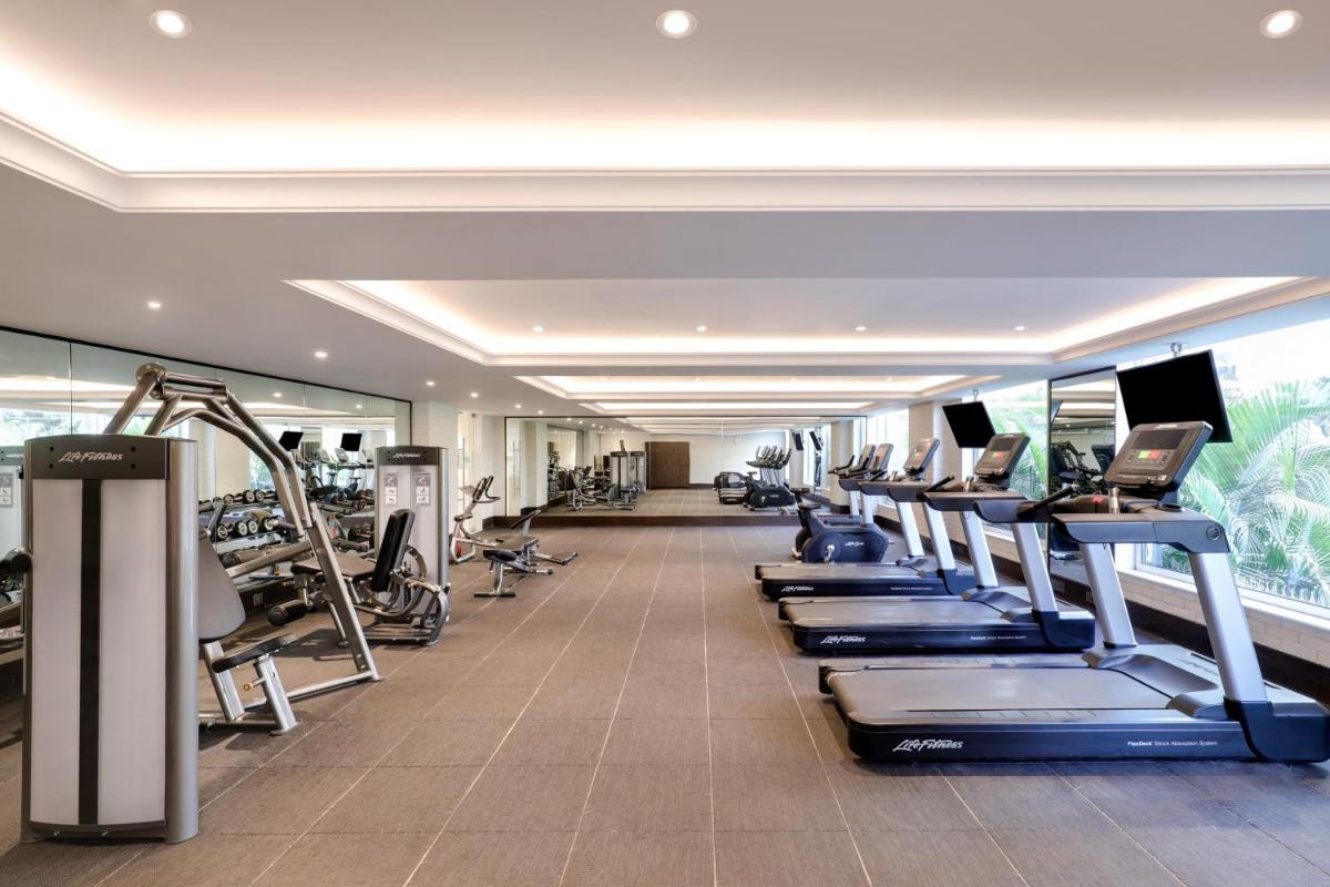 a gym with a row of treadmills and machines at Lemon Tree Premier, Mumbai International Airport in Mumbai