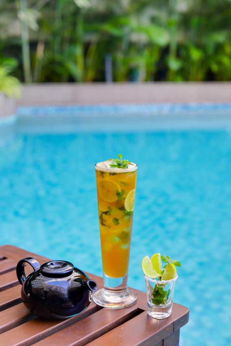 a drink sitting on a wooden table next to a pool at Lemon Tree Premier, Mumbai International Airport in Mumbai