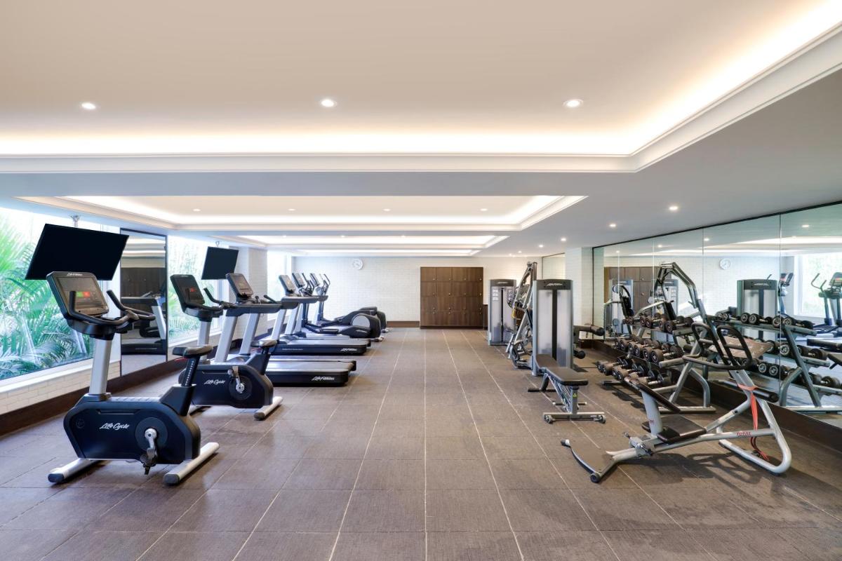 a gym with rows of treadmills and elliptical machines at Lemon Tree Premier, Mumbai International Airport in Mumbai