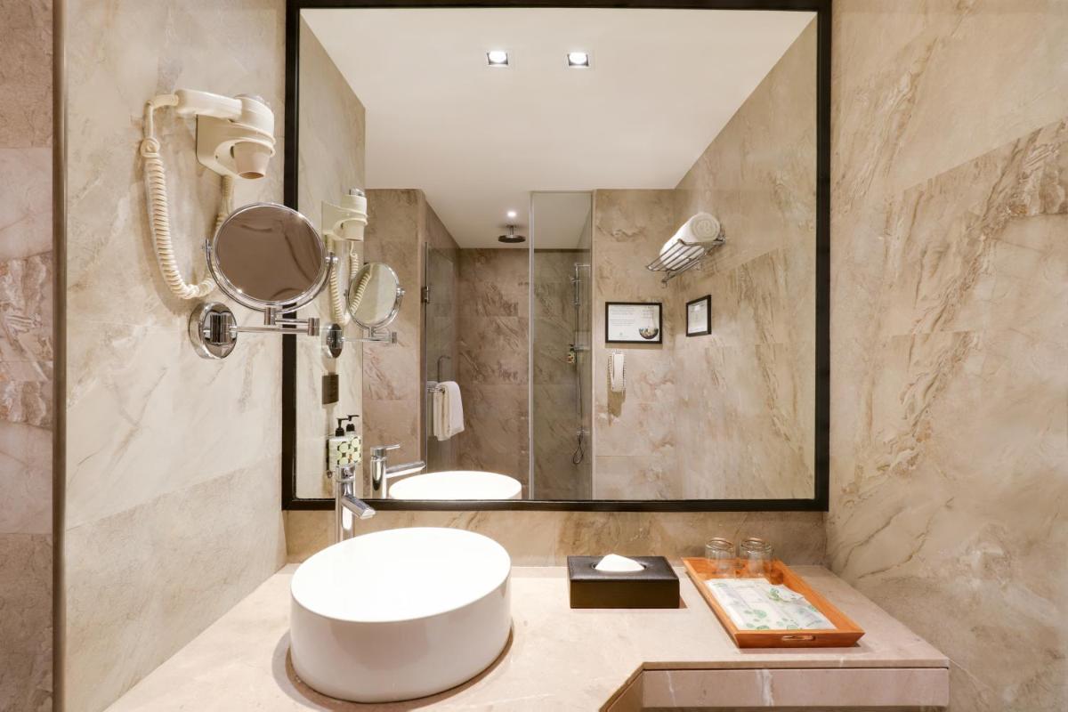 a bathroom with a large mirror and a sink at Lemon Tree Premier, Mumbai International Airport in Mumbai