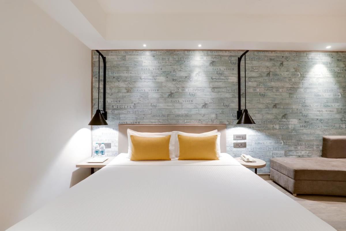 a bedroom with a white bed and a brick wall at Lemon Tree Premier, Mumbai International Airport in Mumbai
