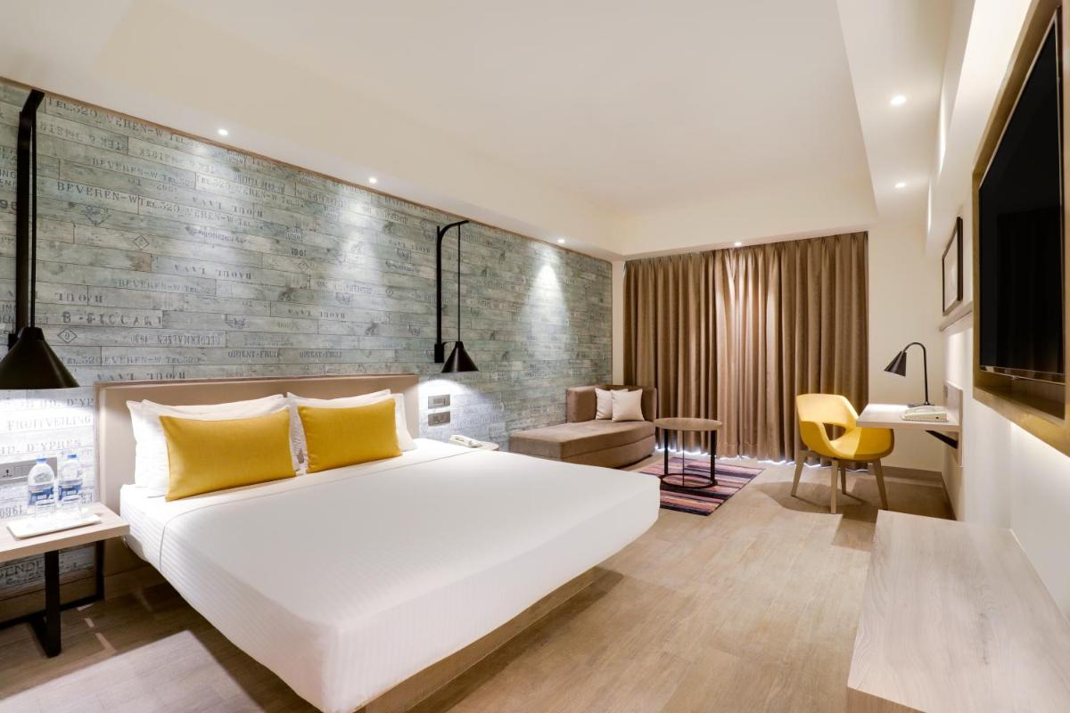 a bedroom with a large white bed and a desk at Lemon Tree Premier, Mumbai International Airport in Mumbai