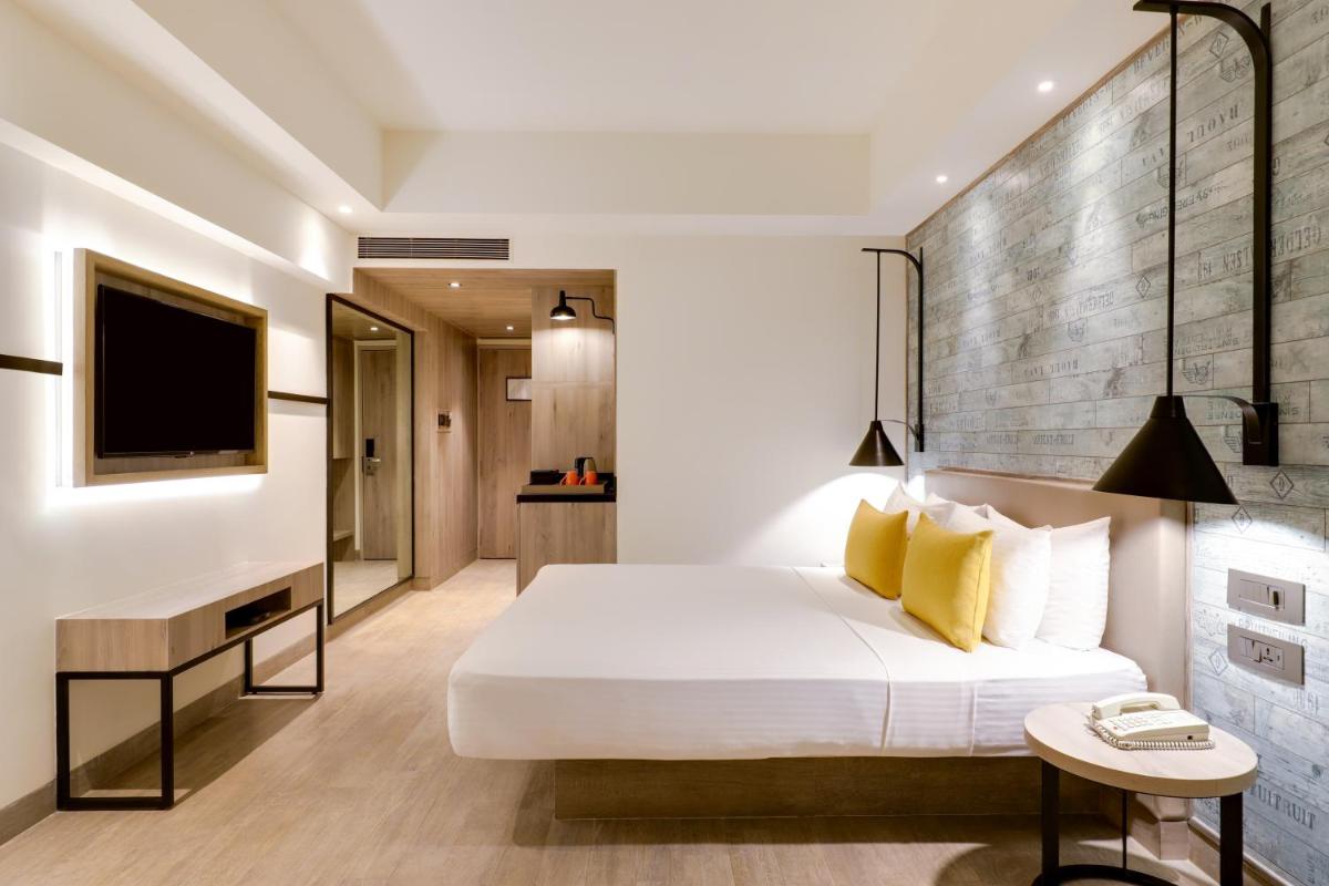 a bedroom with a bed and a desk and a television at Lemon Tree Premier, Mumbai International Airport in Mumbai