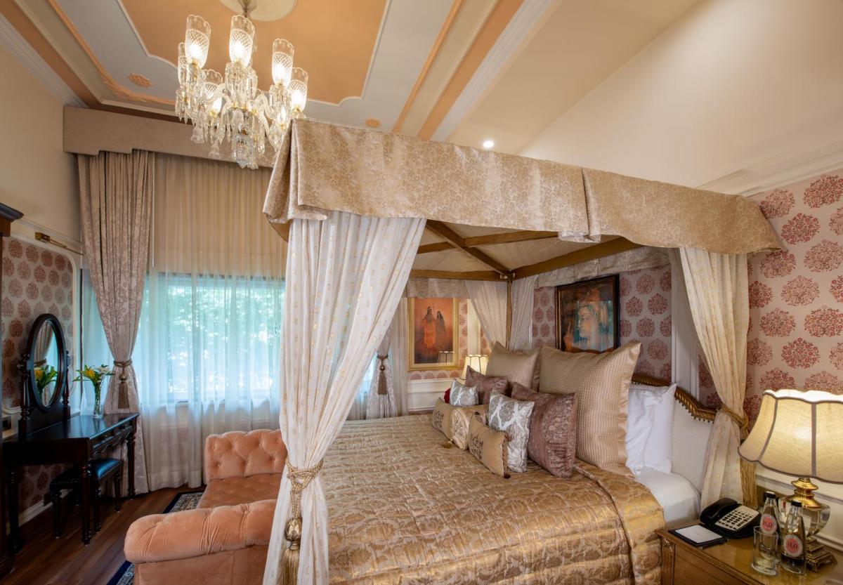 a bedroom with a canopy bed and a chandelier at The Claridges New Delhi in New Delhi a bedroom with a canopy bed and a chandelier at The Claridges New Delhi in New Delhi