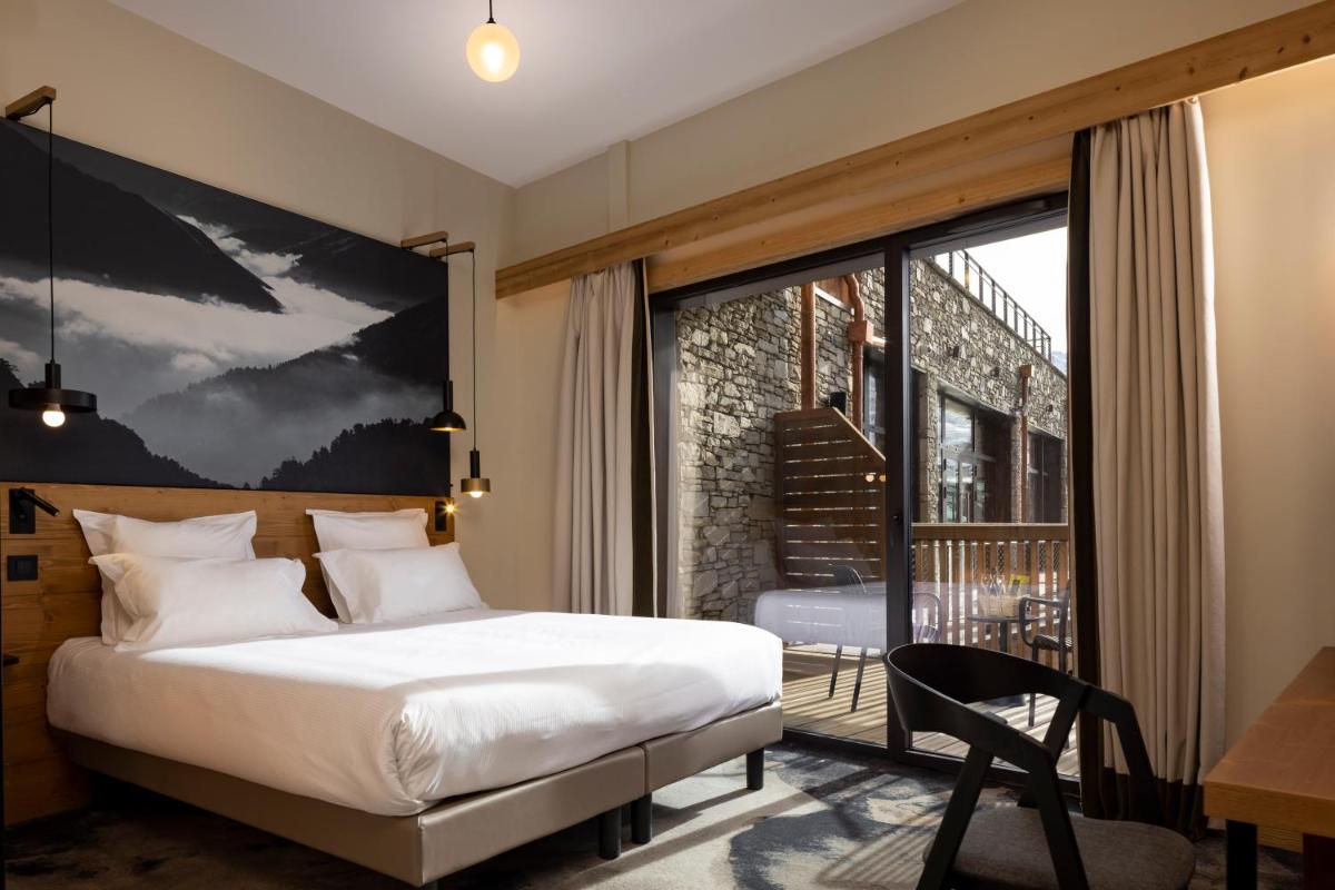 une chambre avec un lit et une grande fenêtre dans l'établissement HIGALIK HOTEL, aux Menuires