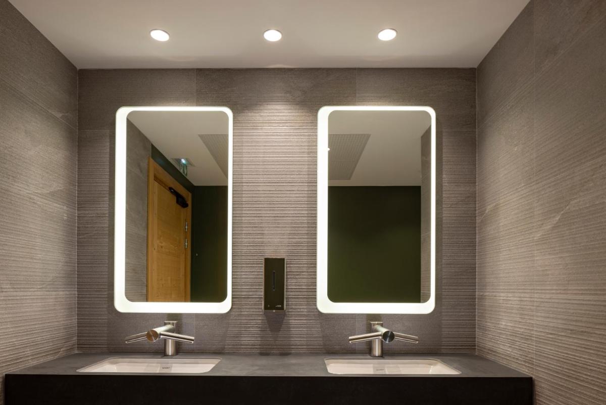 une salle de bain avec deux lavabos et deux miroirs dans l'établissement HIGALIK HOTEL, aux Menuires 39 autres photos