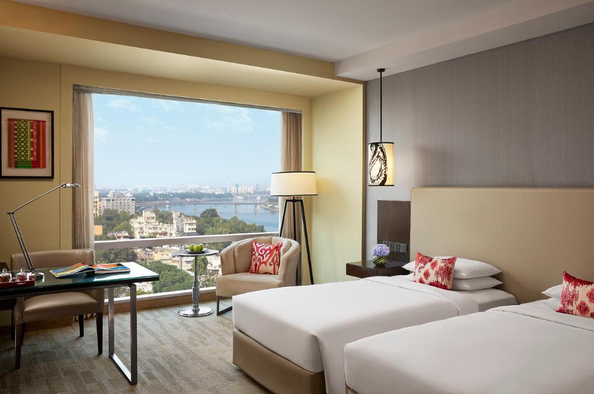 a hotel room with two beds and a large window at Hyatt Regency Ahmedabad in Ahmedabad