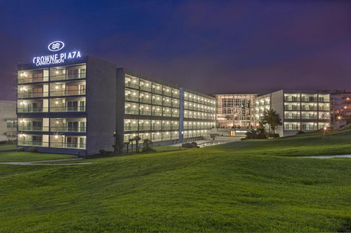 um prédio com uma placa no topo à noite em Crowne Plaza - Caparica Lisbon em Costa da Caparica mais 93 fotografias