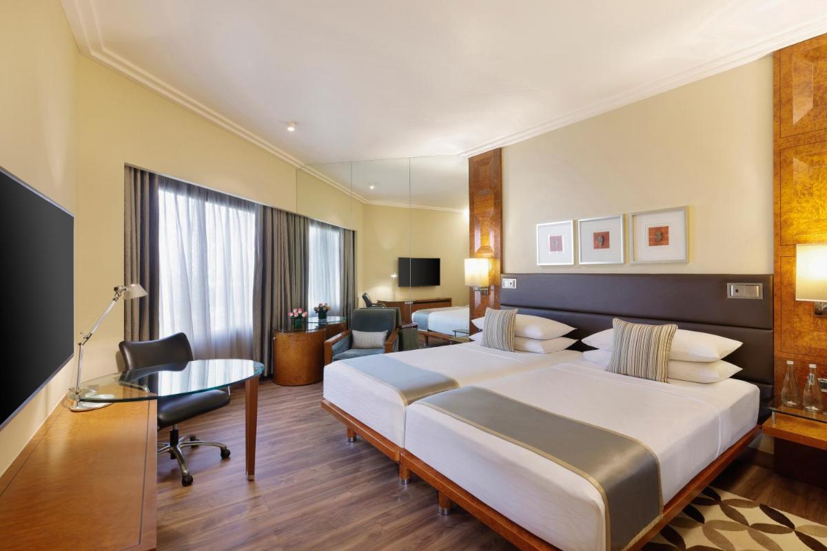 a hotel room with a large bed and a desk at Hyatt Regency Delhi in New Delhi a hotel room with a large bed and a desk at Hyatt Regency Delhi in New Delhi