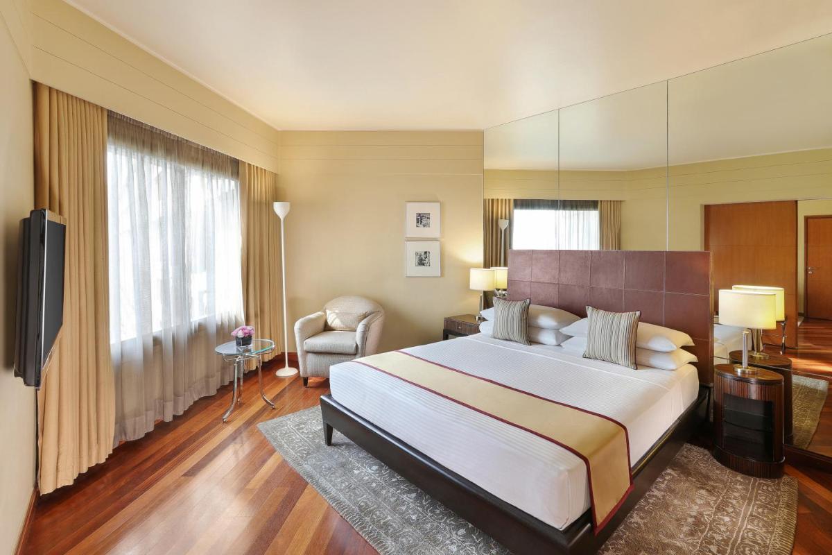 a hotel room with a large bed and a chair at Hyatt Regency Delhi in New Delhi +41 photos a hotel room with a large bed and a chair at Hyatt Regency Delhi in New Delhi +41 photos