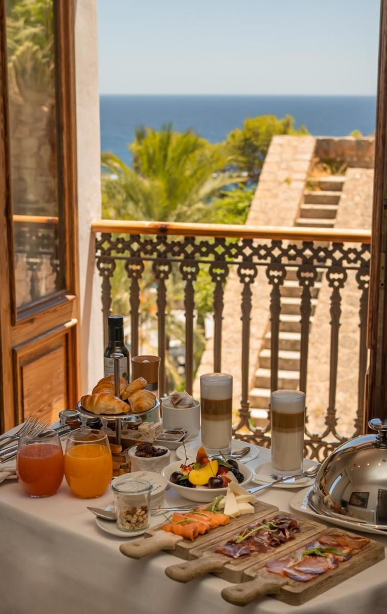 Una mesa con platos de comida y bebidas en un balcón. en Mirador de Dalt Vila-Relais & Chateaux, en Ibiza