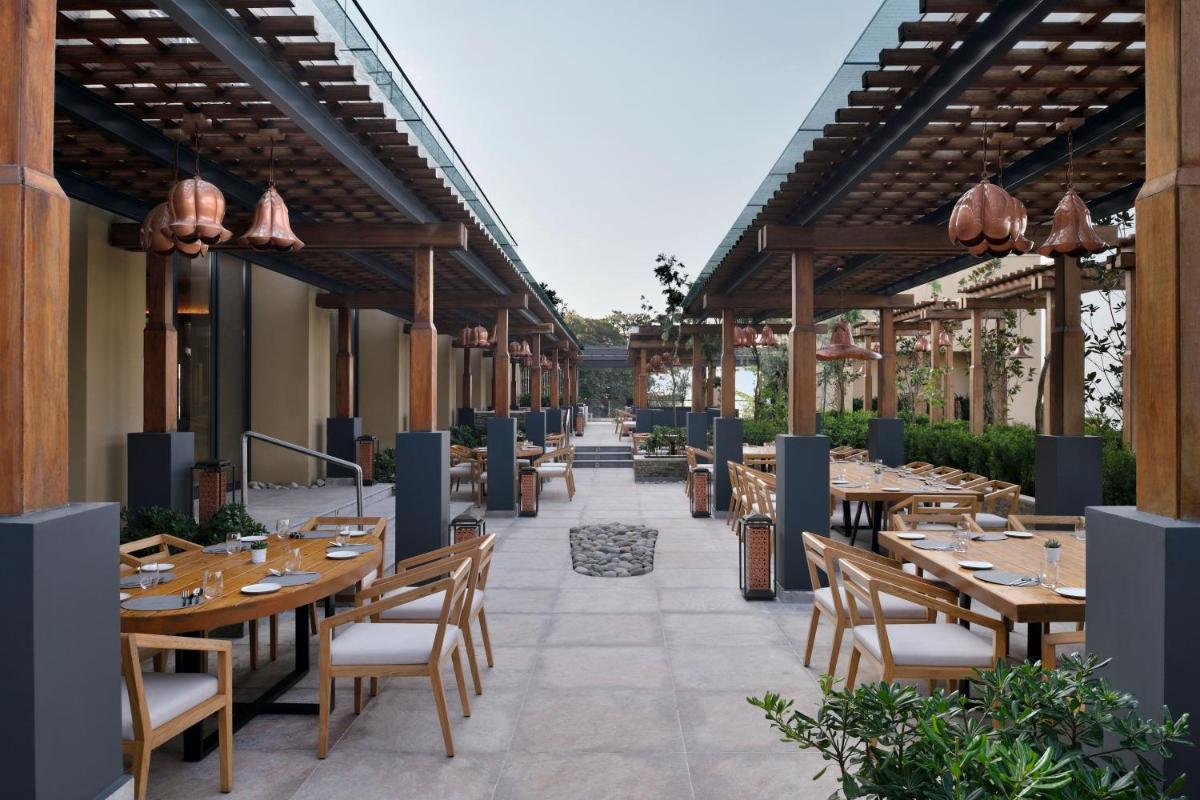 an outdoor patio with wooden tables and chairs at The Westin Resort & Spa Himalayas in Rishīkesh