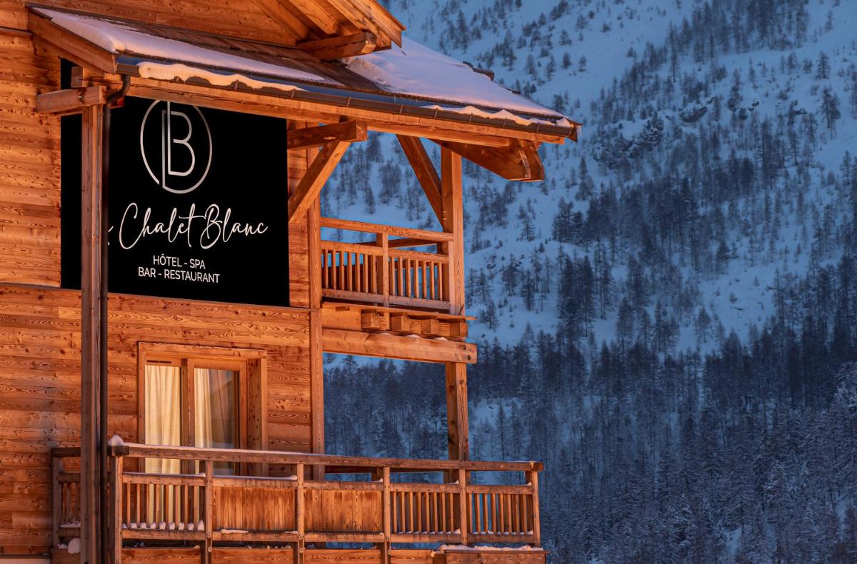 une pancarte sur le côté d'une cabane en rondins dans l'établissement Le Chalet Blanc Hôtel & Spa, à Montgenèvre