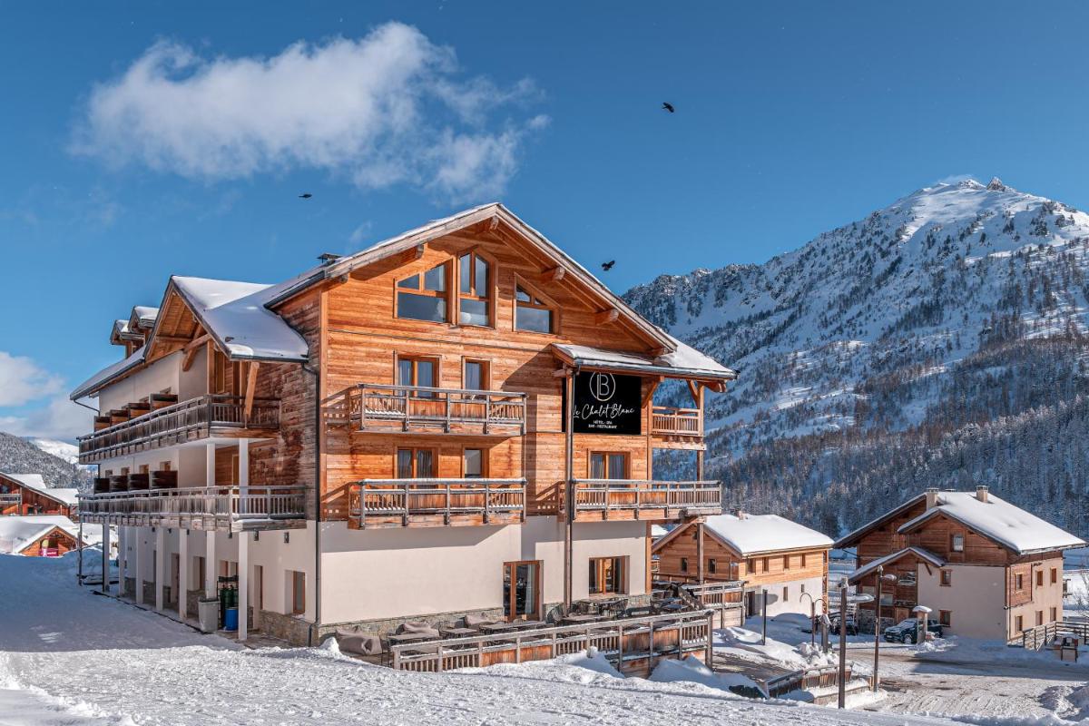 une cabane en rondins sous la neige avec une montagne dans l'établissement Le Chalet Blanc Hôtel & Spa, à Montgenèvre