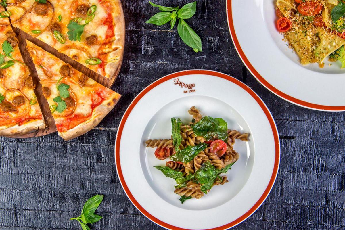 a table with plates of pasta and pizza at Hyatt Regency Delhi in New Delhi a table with plates of pasta and pizza at Hyatt Regency Delhi in New Delhi