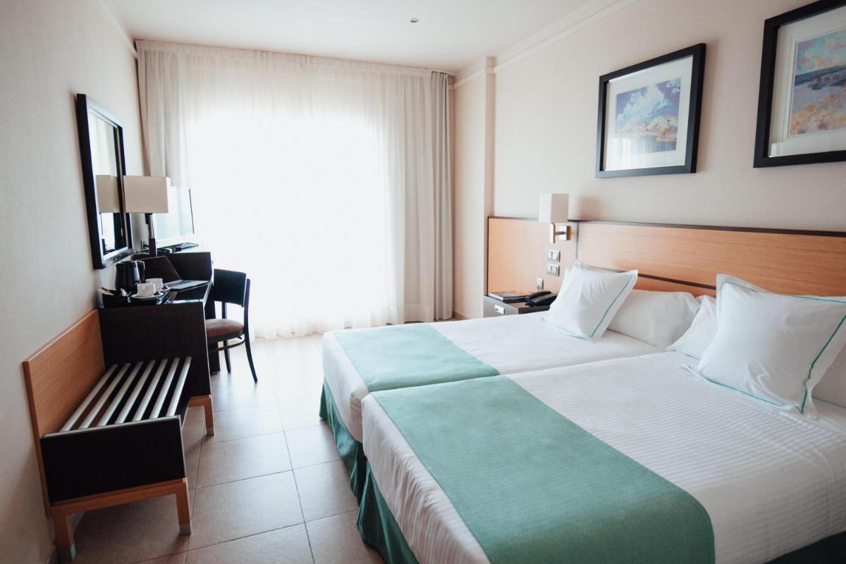 Una habitación de hotel con una cama grande y una silla. en Poseidon La Manga Hotel & Spa - Designed for Adults, en La Manga del Mar Menor