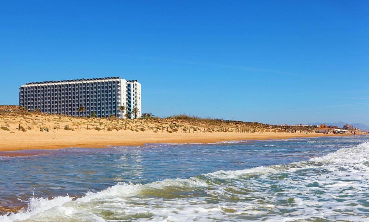 Una vista de una playa con un edificio al fondo. en Hotel Playas de Guardamar, en Guardamar del Segura
